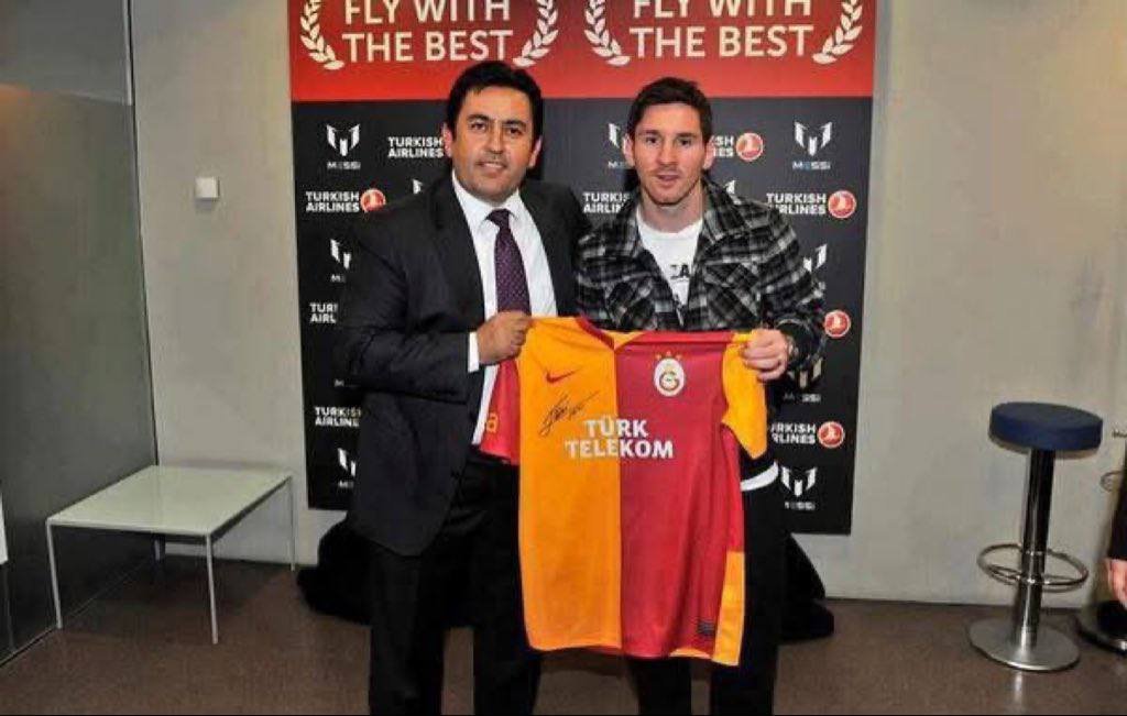 Lionel Messi stands beside former Galatasaray president Ünal Aysal, holding a Galatasaray jersey at a Turkish Airlines promotional event.